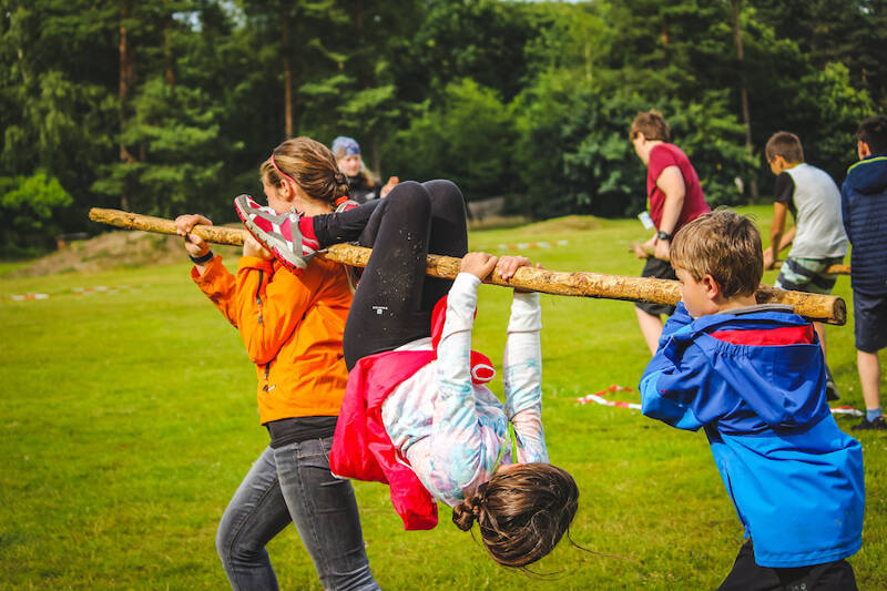 Kinderen dragen elkaar over een hindernissen baan