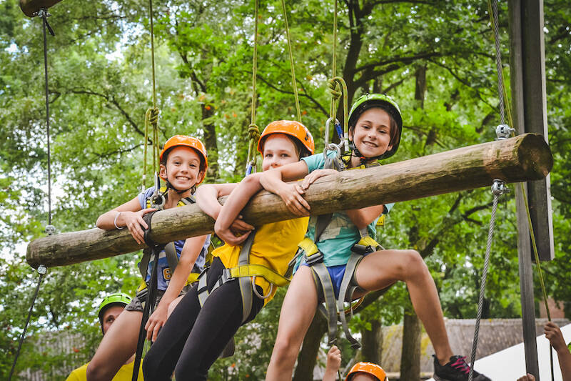 Kinderen klimmen in een bos tijdens ruiterkamp.