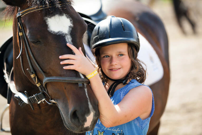 Een meisje knuffelt een paard.