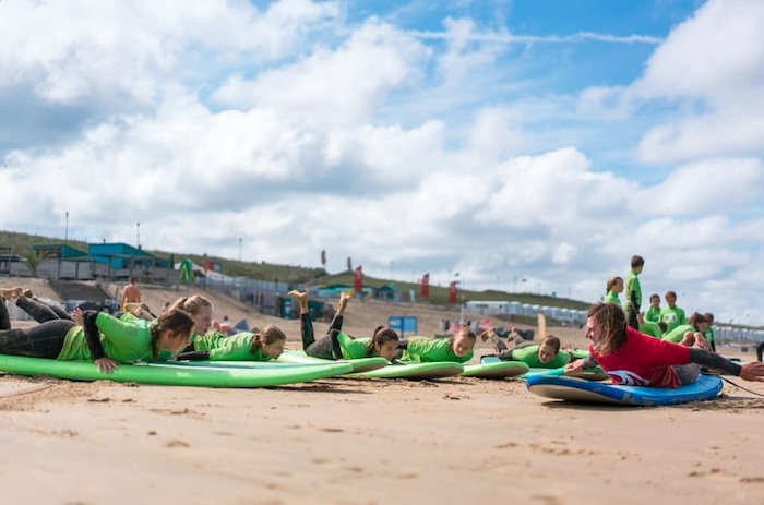Kinderen liggen op het strand en krijgen uitleg van hun begeleider
