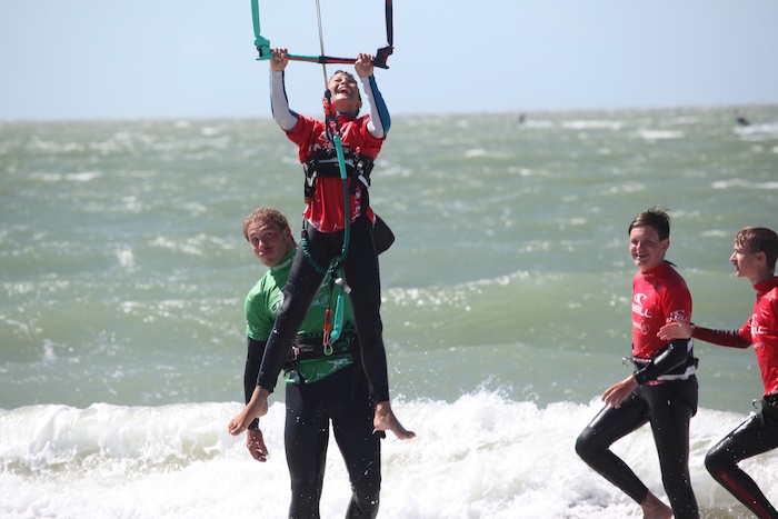 Jongen vliegt de lucht in met kitesurf op surfkamp herfstvakantie