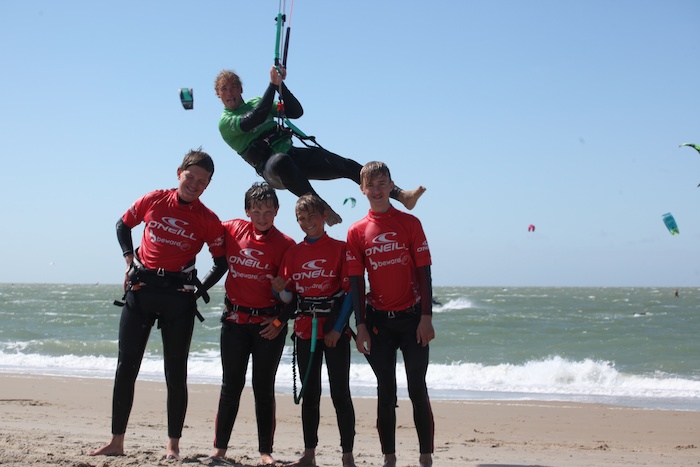 Jongeren poseren met kite tijdens het kitesurfkamp in Zeeland.