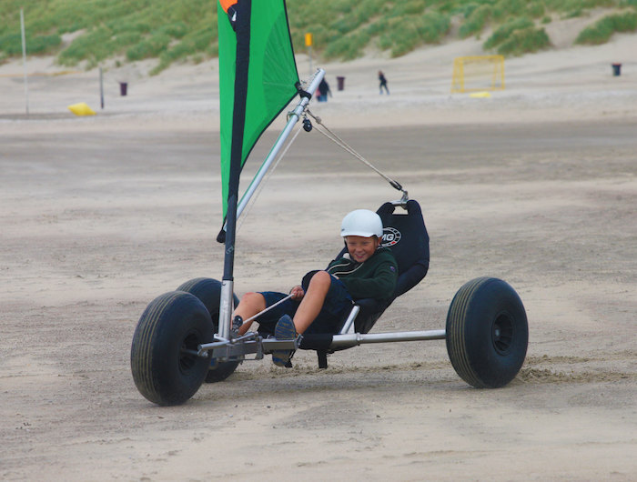 Een jongen aan het blokarten op het strand in Zeeland.