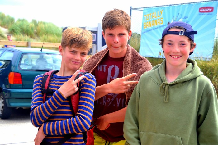 Op golfsurfkamp lachen drie jongens naar de camera