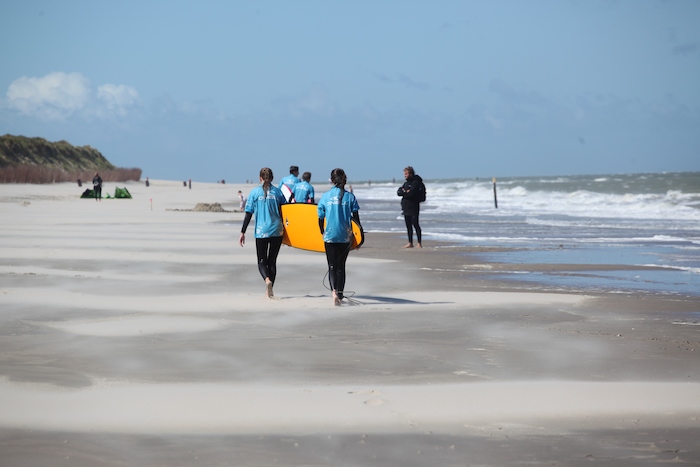 Kinderen dragen een surfboard naar de zee tijdens het surfkamp
