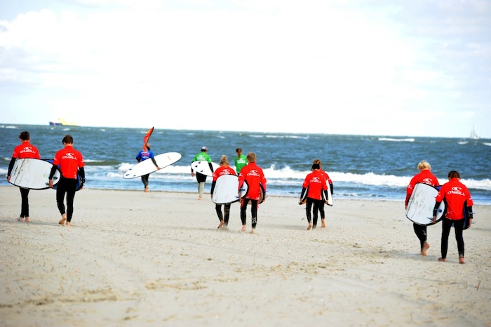 Jongeren maken zich klaar om in de zee te gaan surfen tijdens het surfkamp