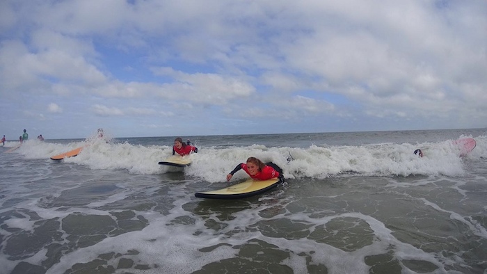Jongeren nemen de golf tijdens het surfen tijdens het surfkamp