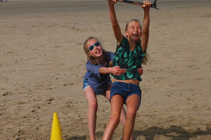 Twee meisjes besturen een kite op surfkamp in Zeeland.