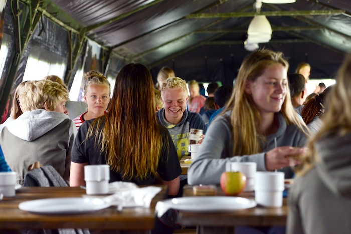 Deelnemers golfsurfkamp zitten in kantine, eten en lachen