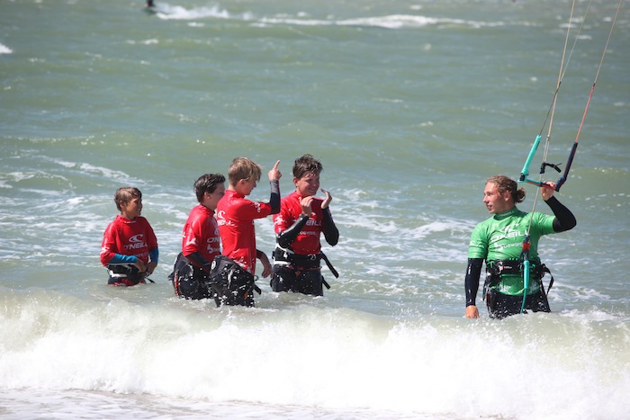 Jongens aan het kitesurfen in de zee tijdens het watersportkamp in Zeeland.