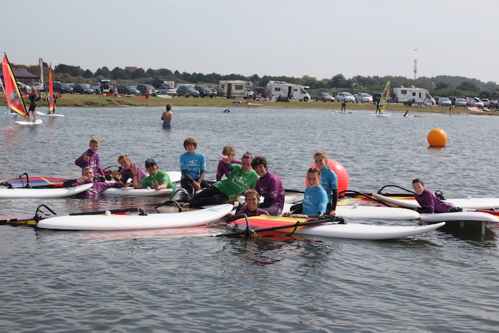Jongeren poseren in het water tijdens het windsurfkamp in Zeeland.