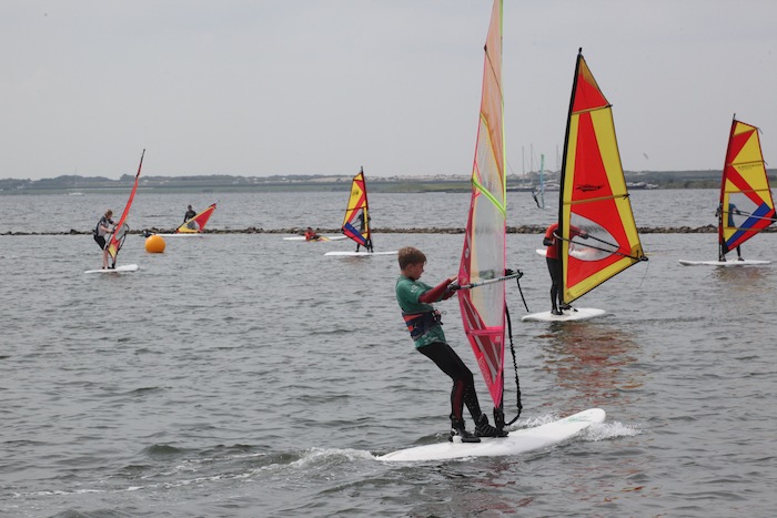 Jongeren surfen tijdens het windsurfkamp in Zeeland.