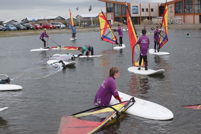 Kinderen leren rechtstaan tijdens het windsurfkamp in Zeeland.