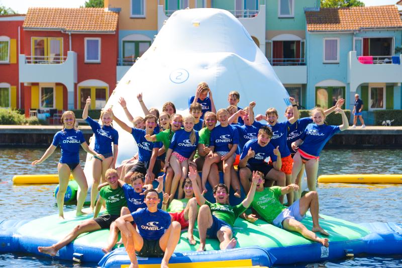 Kinderen op opblaas-attractie in water op watersport vakantie
