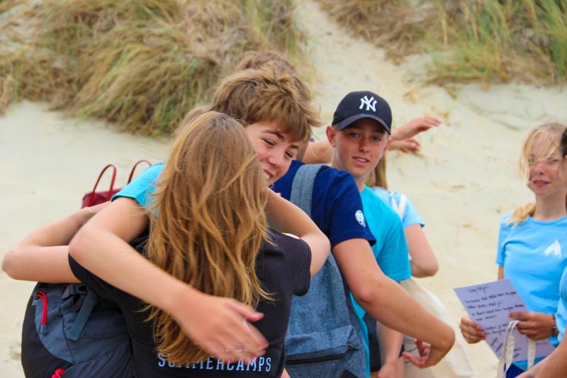jongen en meisje geven elkaar een knuffel tijdens surfkamp zomervakantie