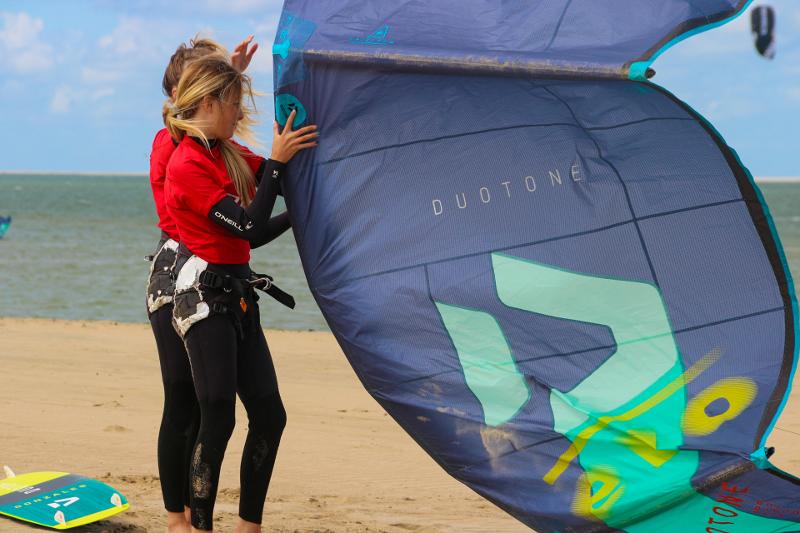meisjes zetten kitesurf klaar tijdens surfkamp zomervakantie