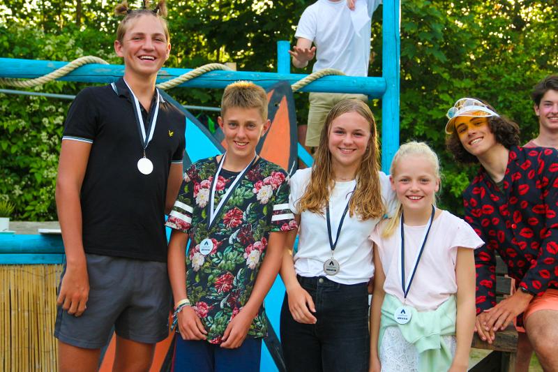meisjes en jongens hebben medaille om en lachen tijdens surfkamp zomervakantie