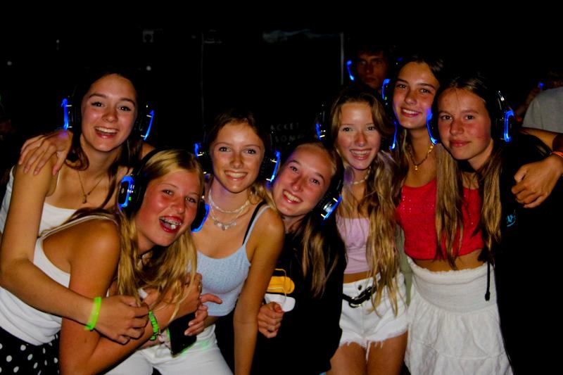 meisjes poseren met koptelefoon tijdens de silent disco tijdens surfkamp zomervakantie