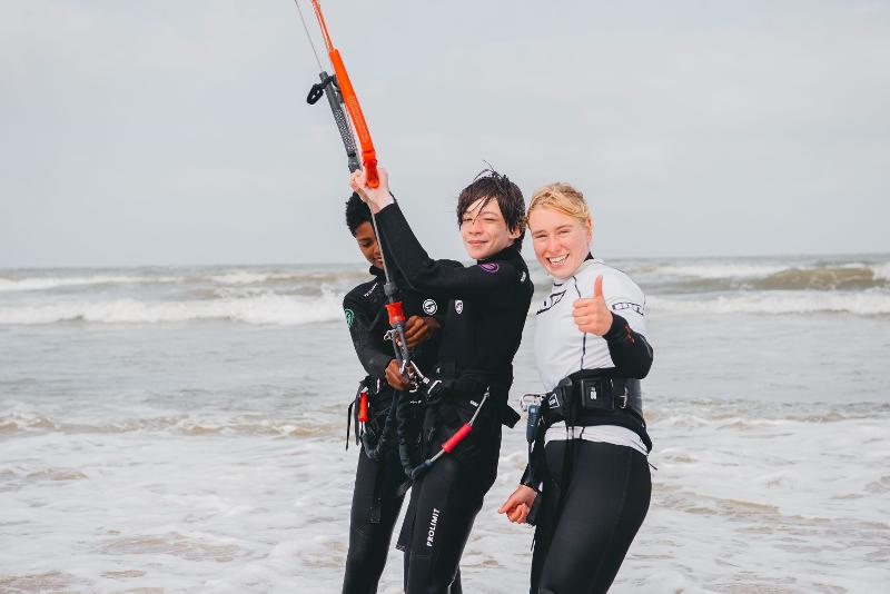 Jongen kijkt naar camera met instructeur op kitesurfkamp Nederland