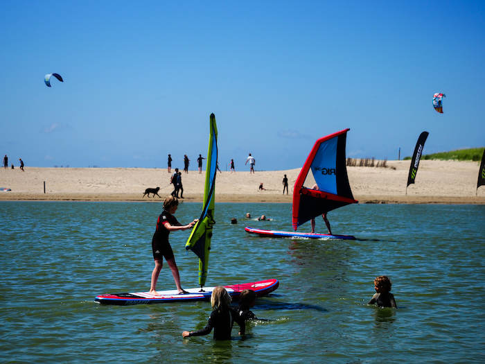 Kinderen krijgen windsurfles tijdens het surfkamp tijdens de zomervakantie