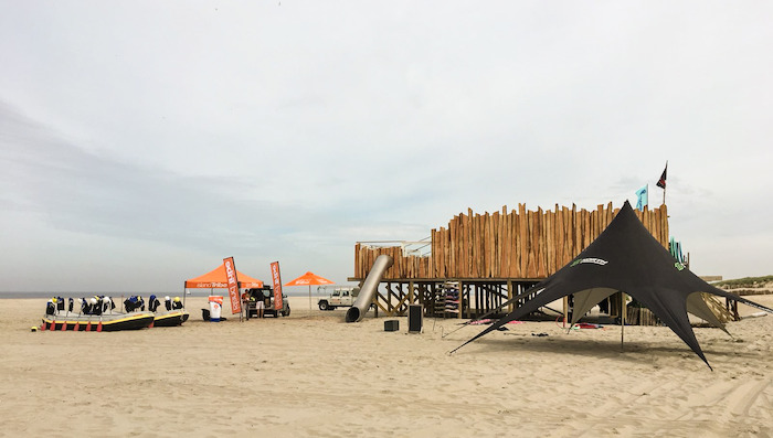 Blik op een strand met zwarte tent tijdens een golfsurfkamp