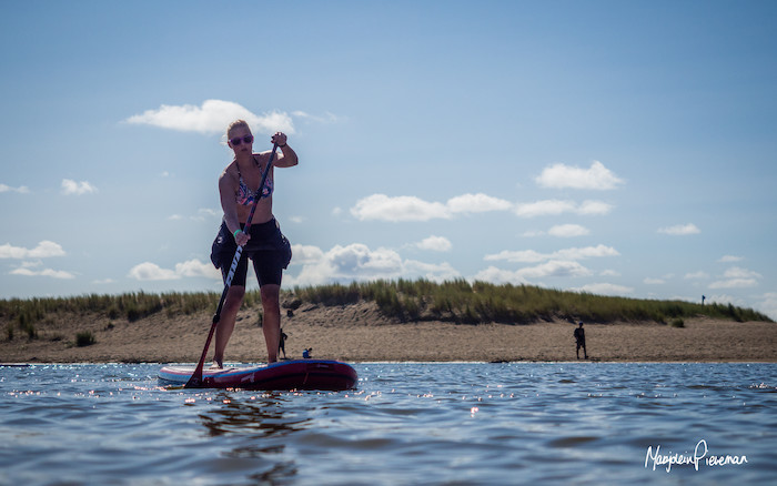 Een dame is aan het suppen aan de kust tijdens een summer camp Amsterdam