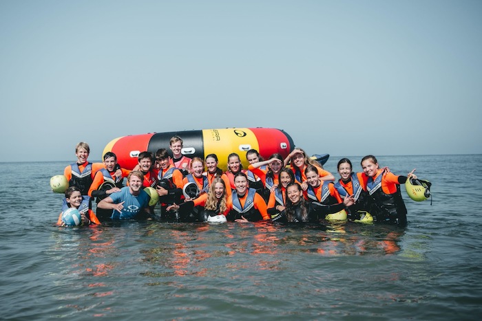 Jongeren op groepsfoto in het water tijdens het watersportkamp in Noord-Holland.