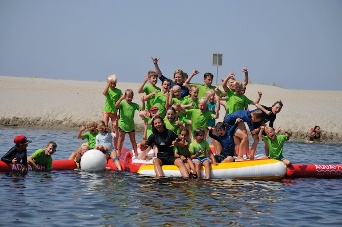 Kinderen poseren op een luchtkussen tijdens het watersportkamp in Noord-Holland.
