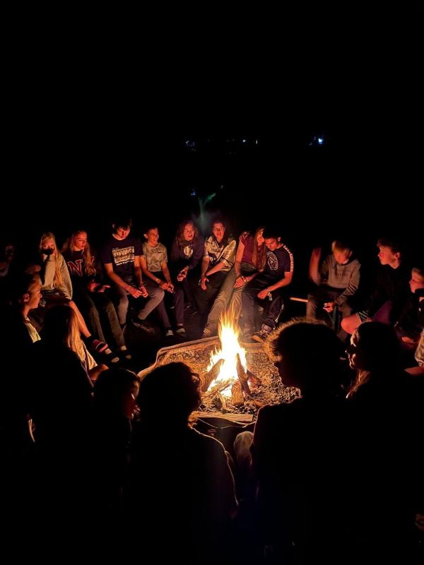 Verhalen delen bij een gezellig kampvuur tijdens het avonturenkamp Gelderland groep kinderen zit bij kampvuur tijdens avonturenkamp Gelderland