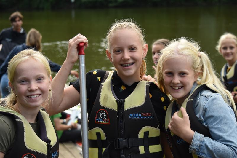 drie meisjes met een zwemvest aan lachen voor een foto tijdens het kanoën tijdens een vakantie voor jeugd