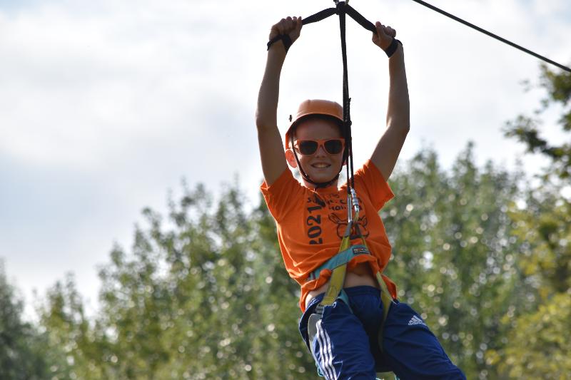 jongen met oranje zonnebril en helm gaat van tokkelbaan tijdens een jongerenvakantie nederland