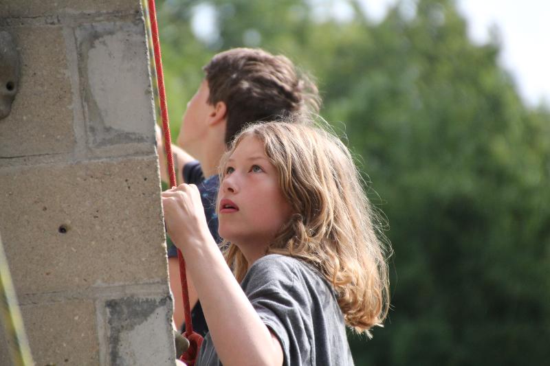 meisje kijkt gefocust naar boven tijdens het beklimmen van de klimmuur tijdens een jongerenvakantie nederland