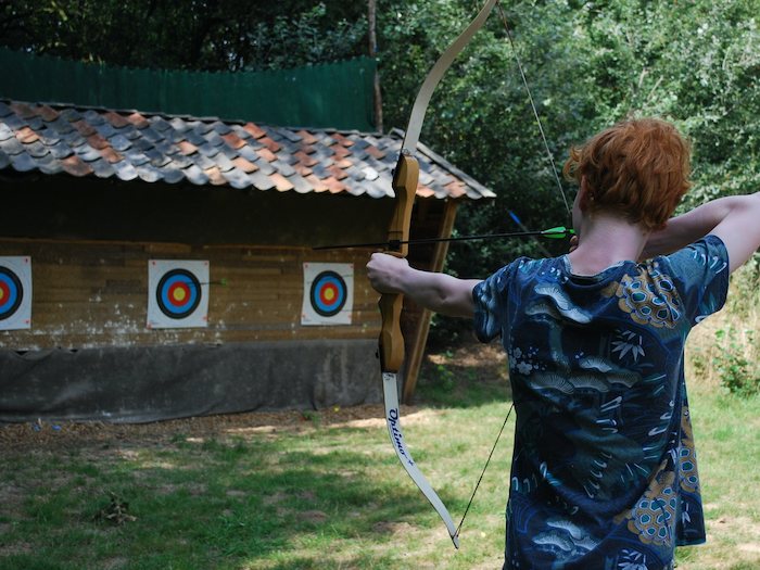 Jongen schiet met pijl en boog tijdens een pretpark kamp