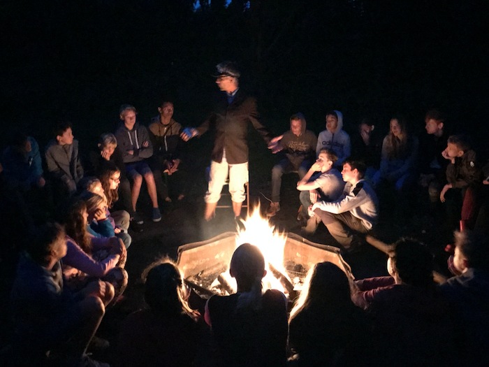Jongeren zitten ’s nachts rond het kampvuur op outdoor kamp