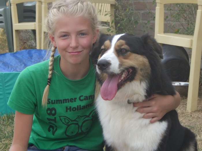Meisje poseert glimlachend met hijgende hond op ponykamp