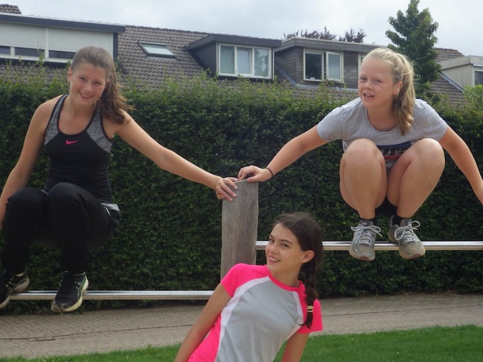 Drie meisjes bij een hindernis op free running zomerkamp in Gelderland.