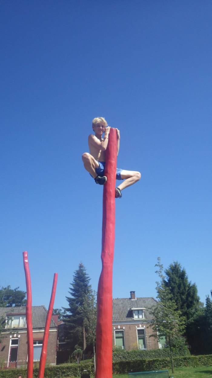 Een jongen klimt op een paal tijdens het free runningkamp tijdens de zomervakantie