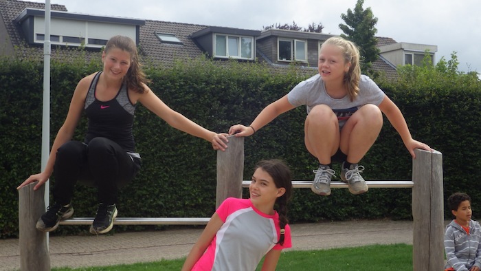 Meisjes poseren op outdoor turntoestellen tijdens het free runningkamp tijdens de zomervakantie