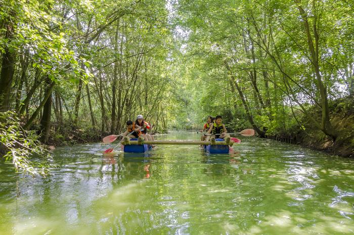 Kinderen varen op een vlot tijdens het zomerkamp in Gelderland.