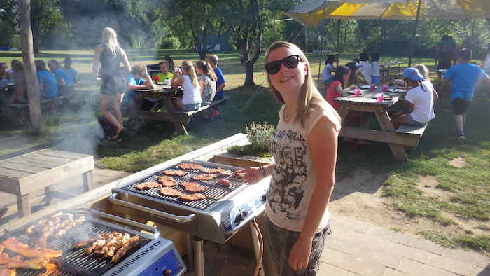 Een meisje bij de bbq in de zon tijdens het zomerkamp in Gelderland.