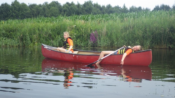 Meisjes varen in kano over rivier tijdens zomerkamp. 