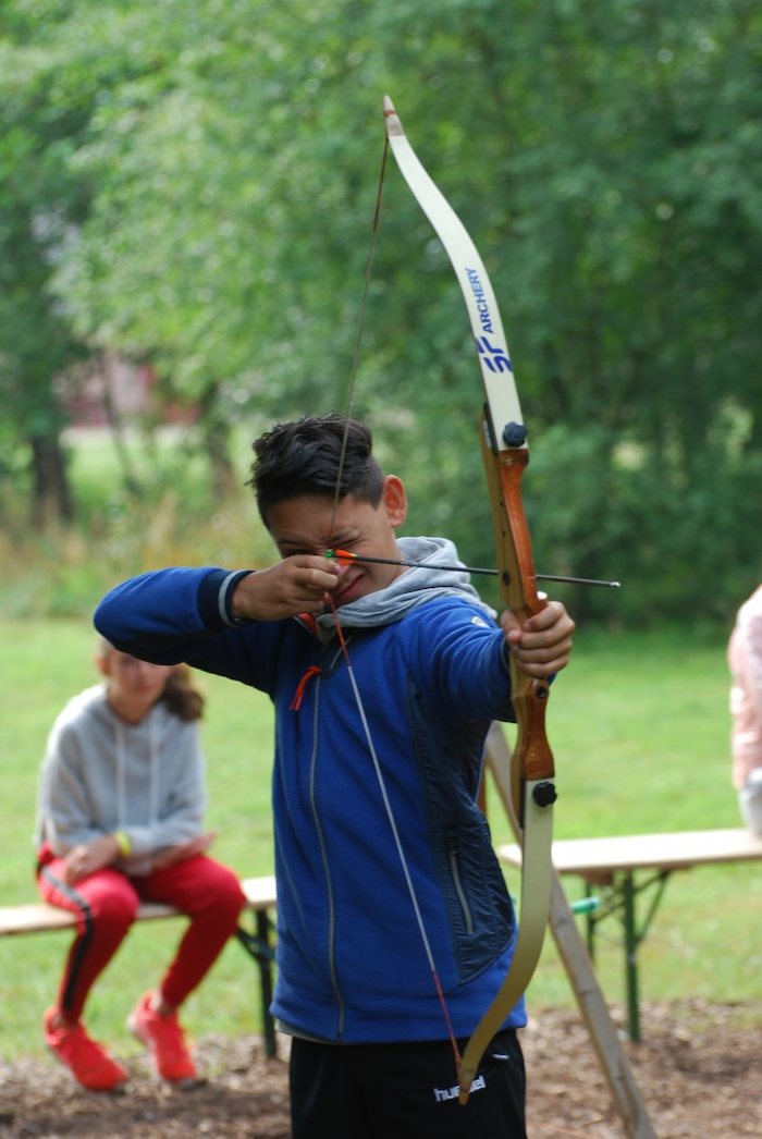 Een jongen leert boogschieten tijdens het avonturenkamp tijdens de zomervakantie