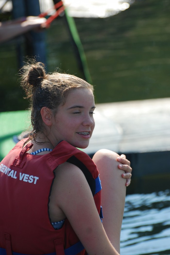Een meisje poseert met haar zwemvest tijdens het wakeboardkamp tijdens de zomervakantie in Gelderland