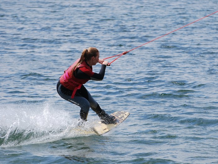 Meisje op een wakeboard in volle vaart op wakeboardkamp in Gelderland tijdens de zomer.