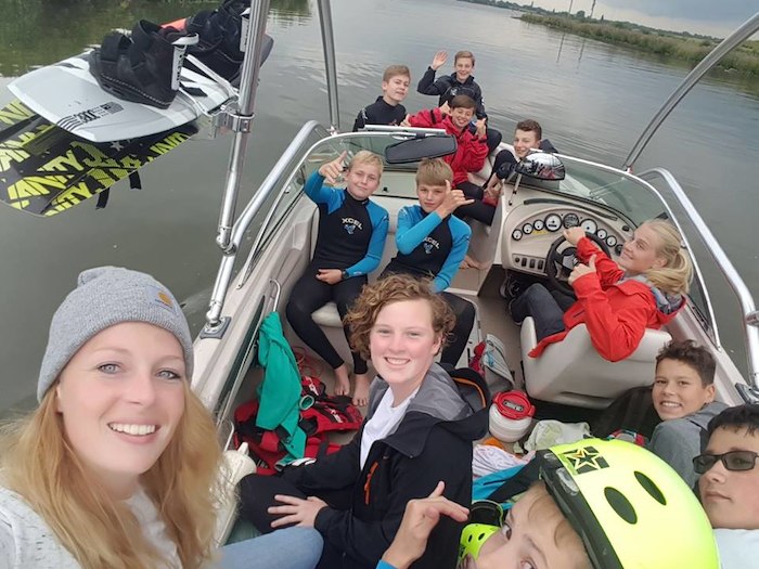 Groep meiden maken lachend naar de camera op watersportkamp.