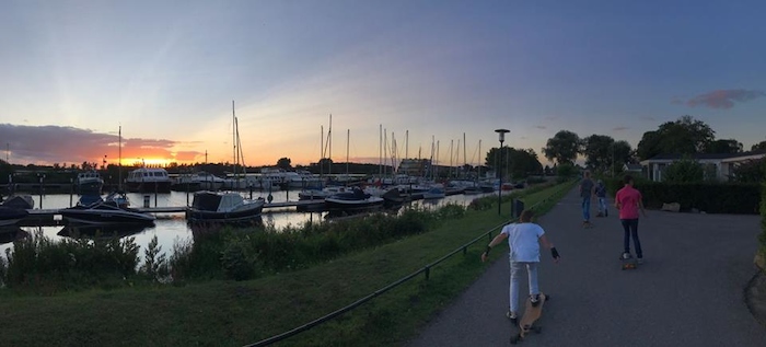 Blik op ondergaande zon, boten op watersportkamp.