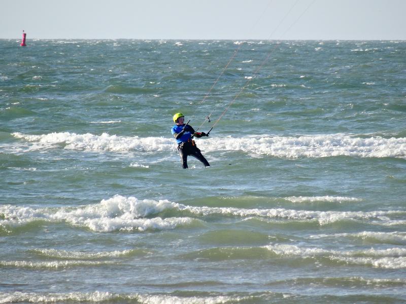 Een beginnende kitesurfer in de midden van de golven op kitesurf vakantie beginners