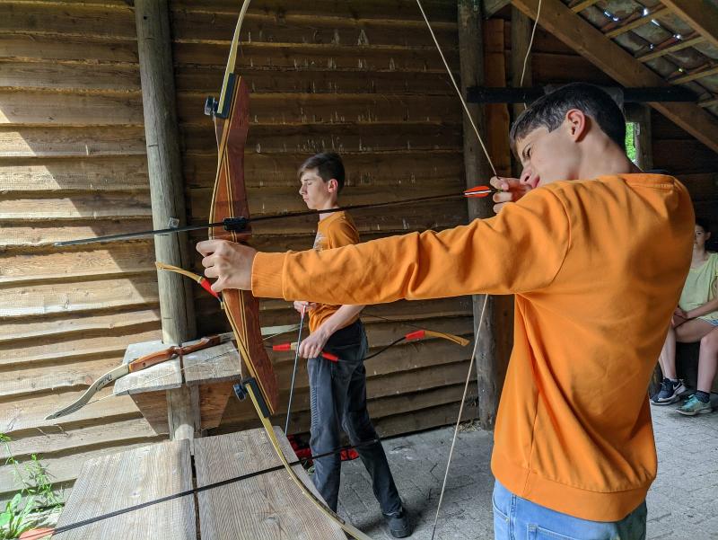 Een jongen schiet een pijl en boog tijdens een bushcraft kamp