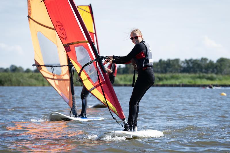 Een meisje aan het windsurfen tijdens een surfkamp in Nederland voor 13 jaar