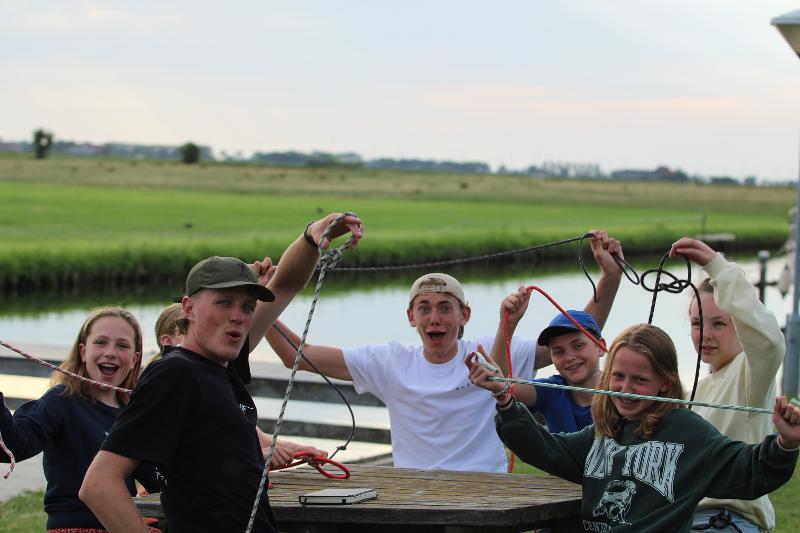 Een groep vrienden leert een touw knopen tijdens een surfkamp in Nederland voor 13 jaar.